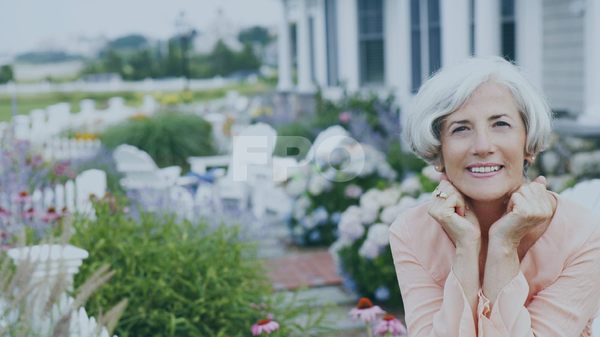 senior-aged female smiling at camera, garden in background